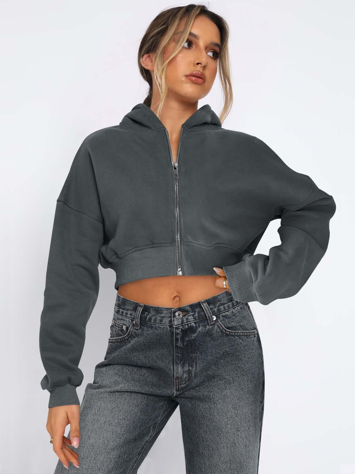 Casual street style model in a cropped gray fleece zip-up hoodie paired with high-waisted jeans. Perfect for spring and fall.